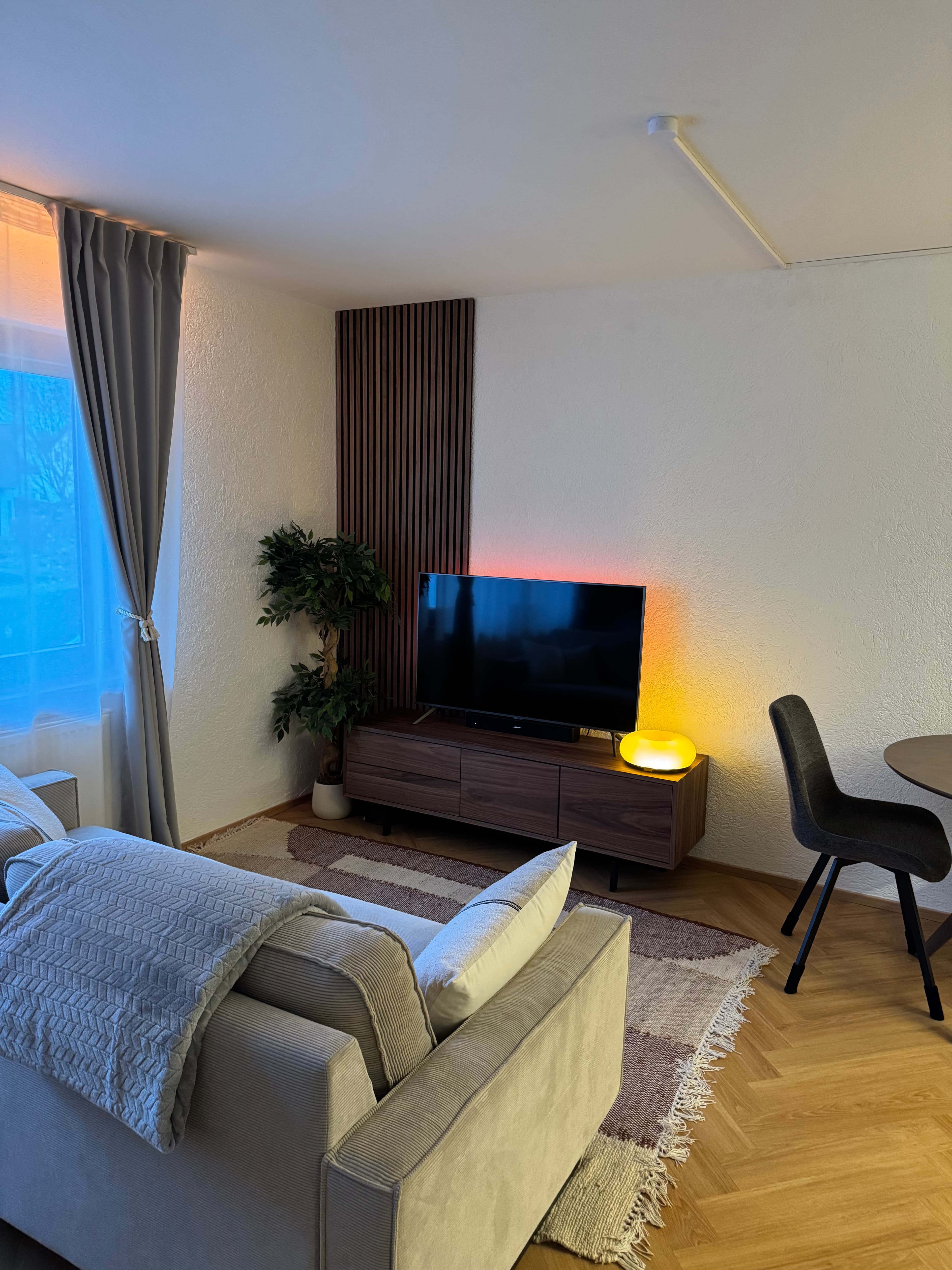 Wohnzimmer mit Sofa, Walnut-Sideboard und warmem Lampenlicht